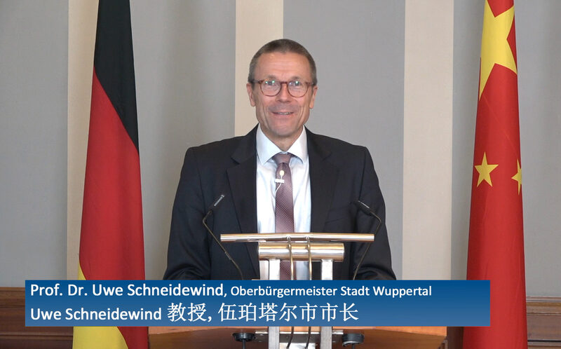 Oberbürgermeister Schneidewind am Rednerpult. Links von ihm eine China-Flagge, rechts eine Deutschland-Fahne.